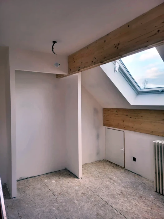 Chantier de rénovation dans combles aménagés avec poutres apparentes en bois massif