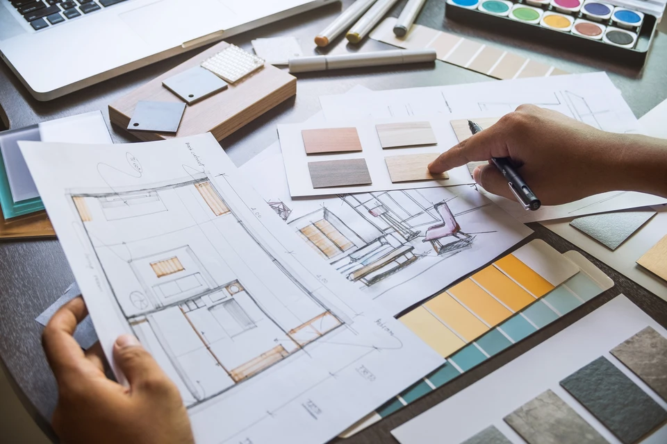 Espace de travail d'architecte d'intérieur avec mains dessinant sur plans techniques