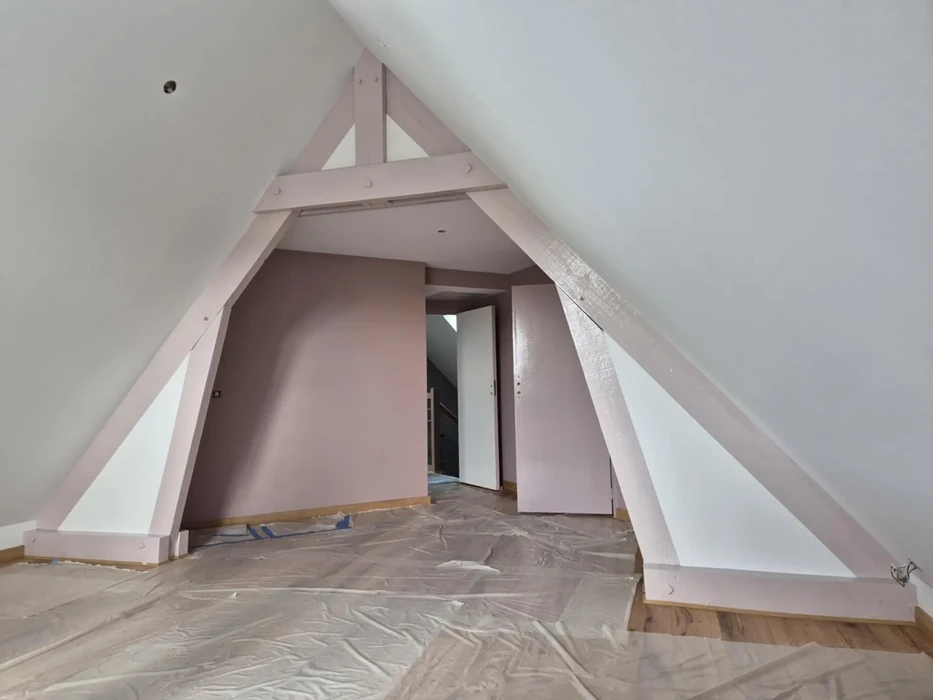 Combles aménagés en cours de finition avec charpente apparente en bois peint