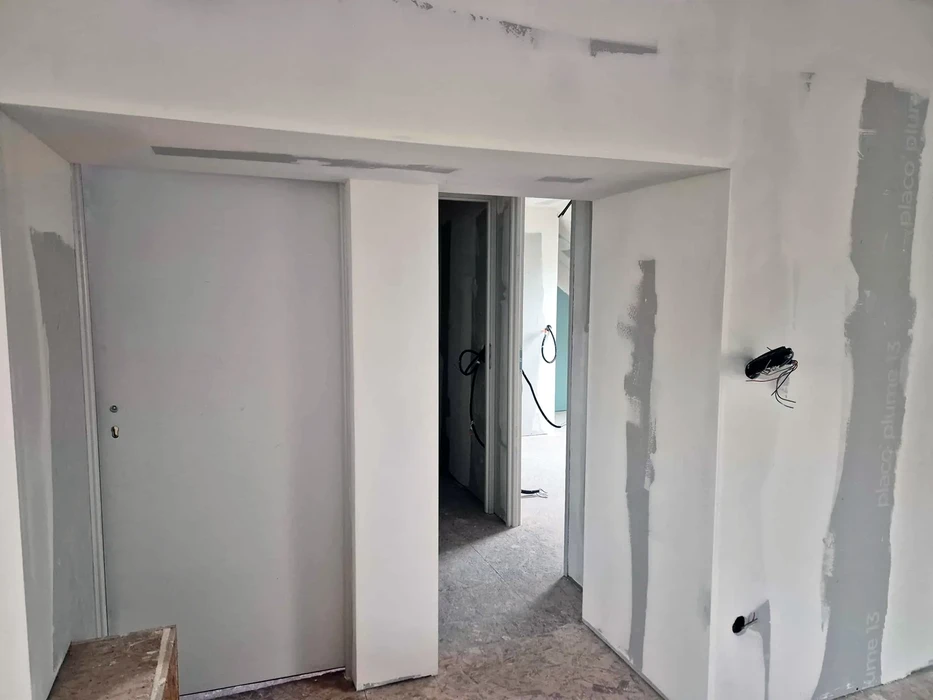 Intérieur d'appartement en cours de rénovation avec murs en plâtre blanc partiellement finis