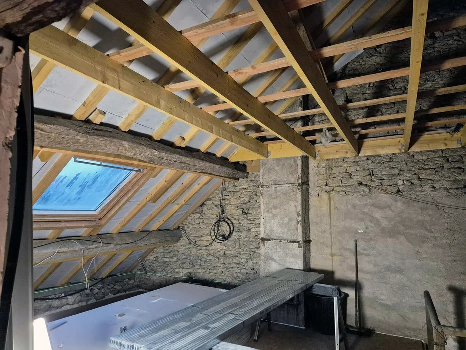 Chantier de rénovation de combles avec charpente traditionnelle en cours de restauration