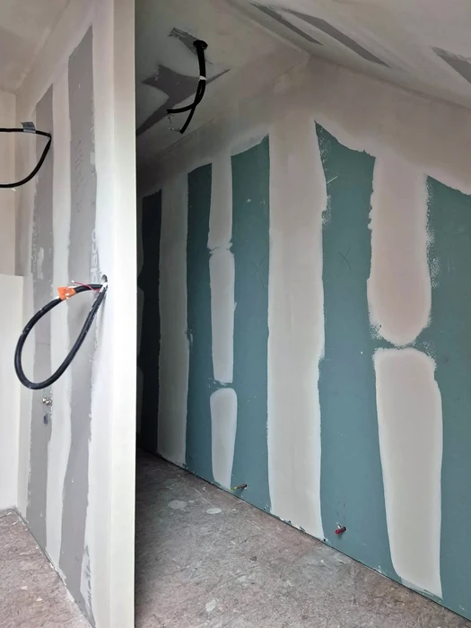 Chantier de construction intérieure avec ouvriers installant cloisons sèches