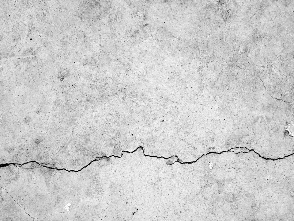 Mur en béton gris présentant une fissure horizontale importante traversant la surface de part en part