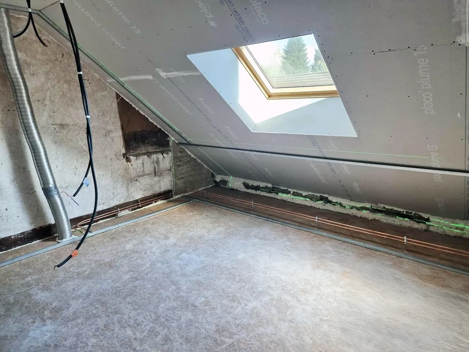 Combles en rénovation avec charpente apparente et fenêtre de toit