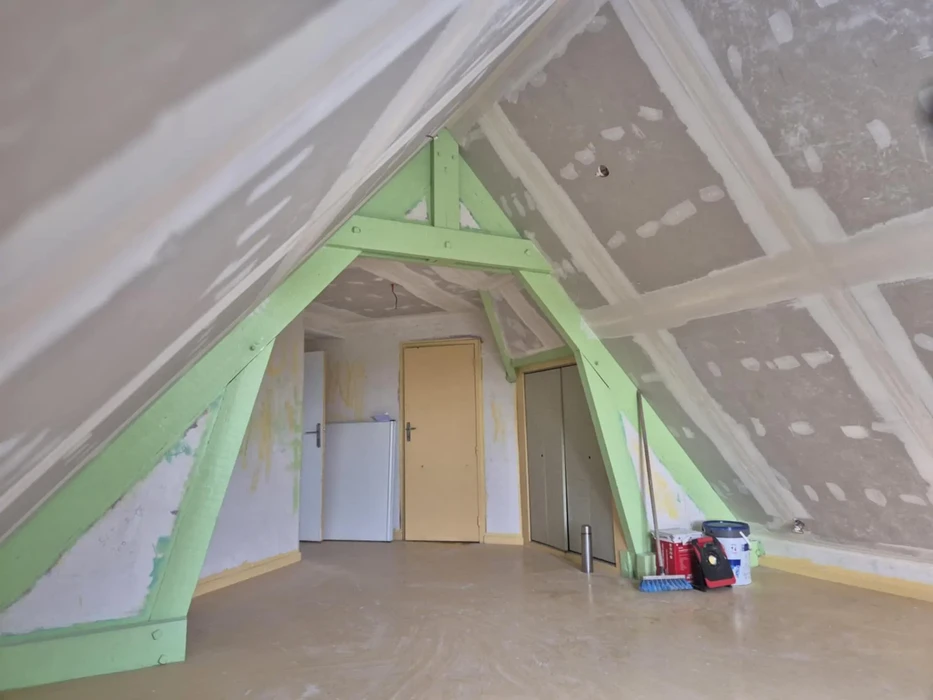 Combles aménageables en cours de rénovation avec charpente apparente peinte en vert pomme