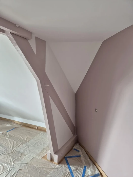 Intérieur d'une maison en cours de rénovation avec escalier en bois peint en beige-rosé