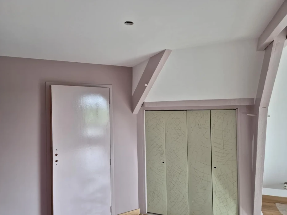 Intérieur résidentiel en cours de finition avec murs peints en rose poudré et blanc