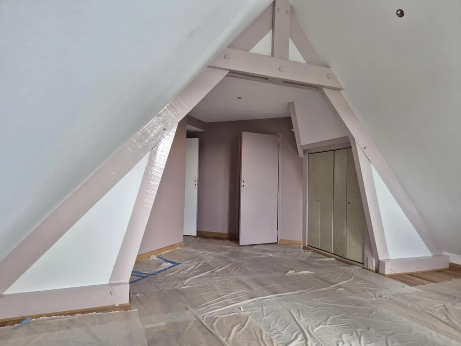 Chambre sous combles aménagés avec poutres apparentes peintes en vert, plafond en lambris bois blanc