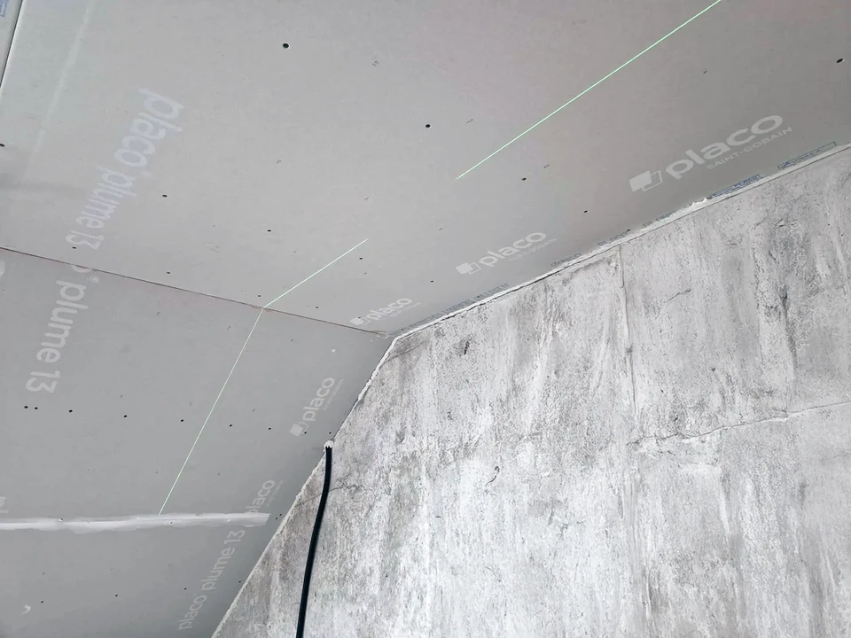 Chantier de rénovation dans combles avec ouvrier en vêtement rouge sur échafaudage