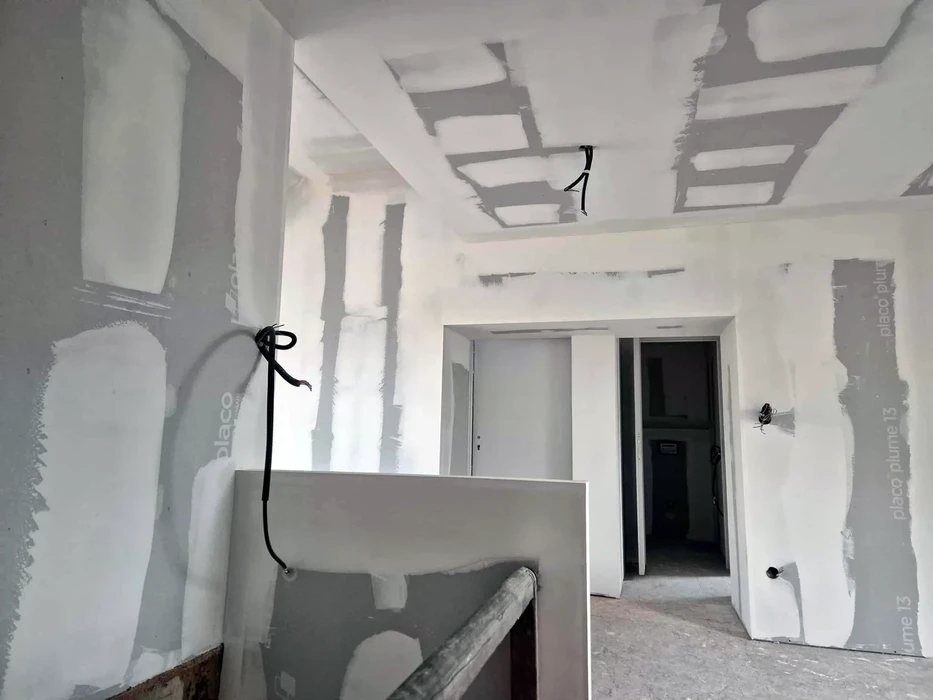 Intérieur résidentiel en cours de finition avec murs peints en rose poudré et blanc