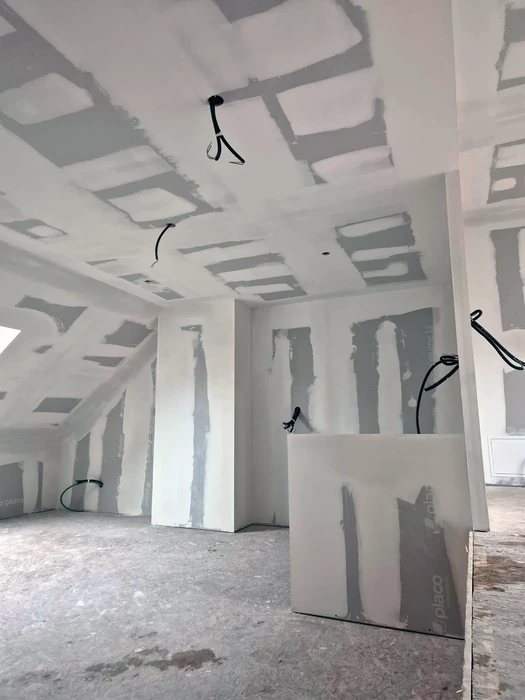 Chantier de construction intérieur avec ouvrier installant des gaines de ventilation métalliques flexibles