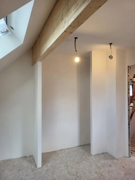 Combles en cours d'aménagement avec charpente apparente et fenêtre de toit installée