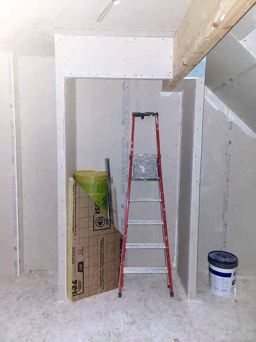 Combles aménagés en cours de finition avec charpente apparente peinte en blanc